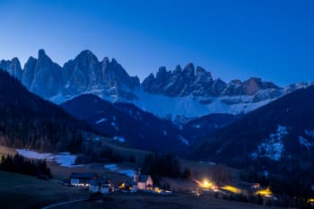 A small village nestled in a mountain valley at dusk.